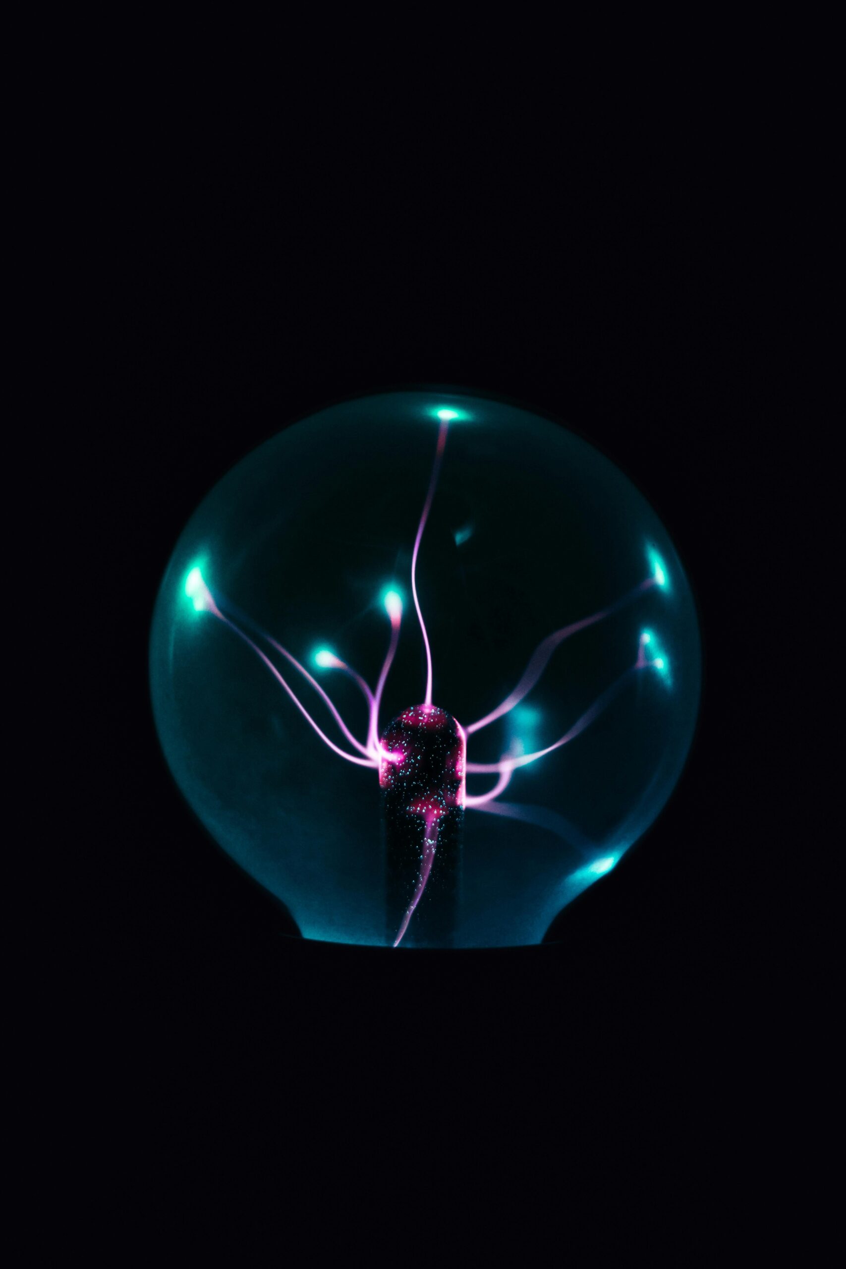 Mystical plasma ball emitting colorful electric tendrils in dark room, perfect for science-related visuals.