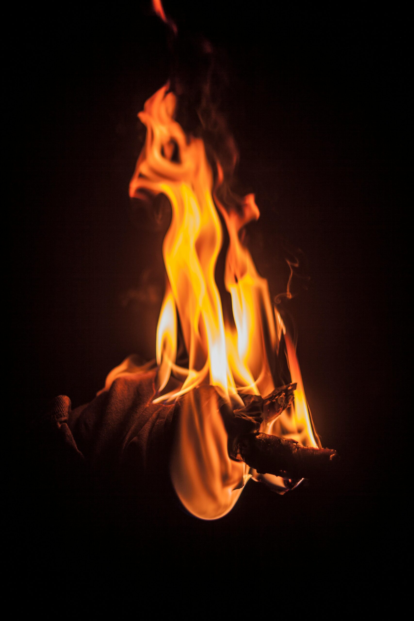 Intense close-up shot of vibrant flames engulfing firewood against a dark background.
