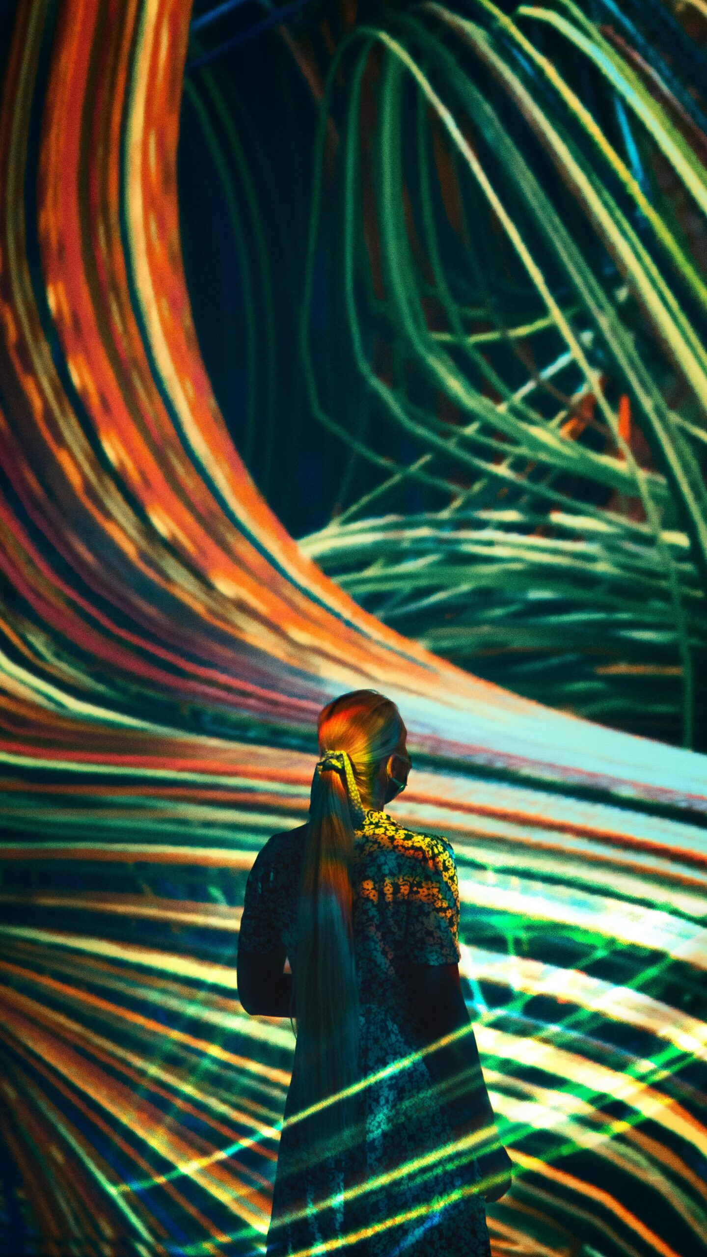 A woman immersed in vibrant digital light art, creating a dynamic abstract scene.